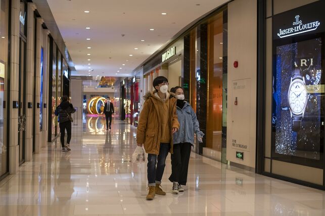 Dos jóvenes chinos con mascarillas pasean por un centro comercial prácticamente vacío en Shangay.